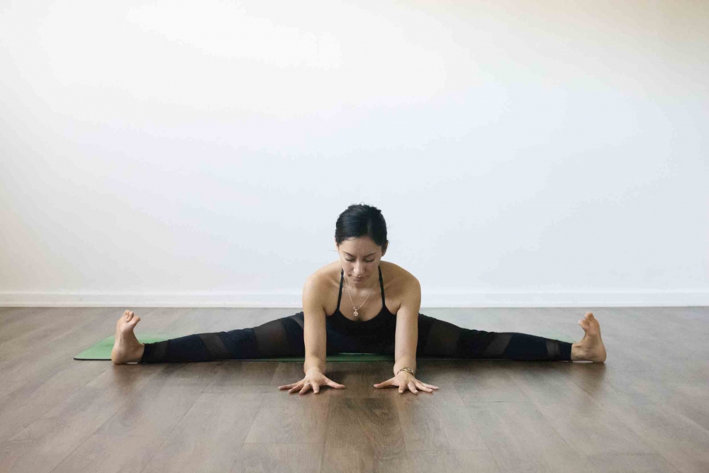 straddle yoga  with Female yogi on green yoga mat